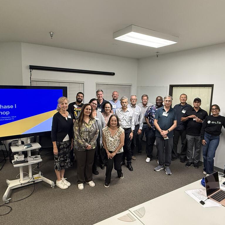 Group photo of UC Riverside's inaugural SBIR Phase I Workshop participants, instructors, and mentors standing together beside a presentation screen during the October 7, 2026 session.