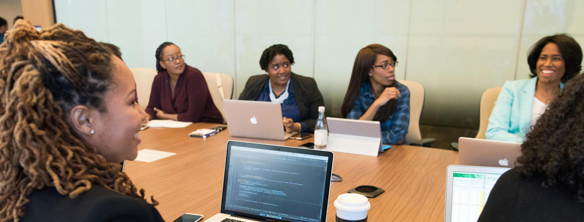 A collaborative group of women entrepreneurs and startup founders gathered around a circular conference table during a professional business discussion. The scene reflects innovation, mentorship, and strategic conversations around startup growth, research commercialization, and federal funding opportunities in a modern entrepreneurial setting.